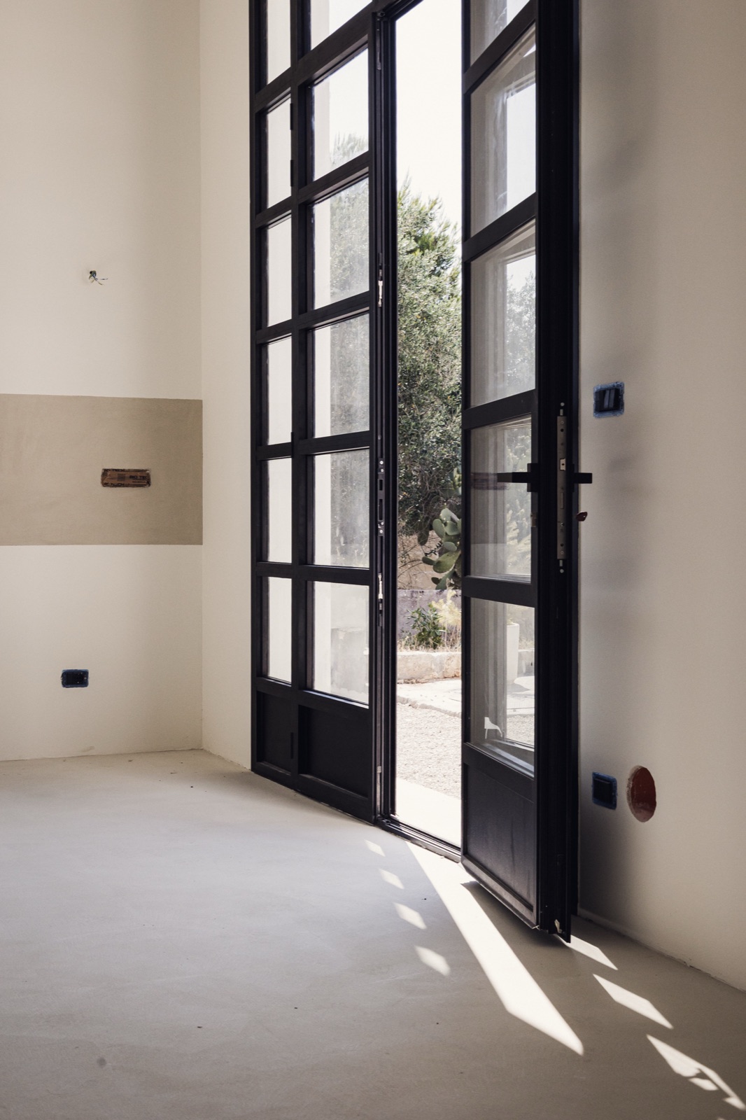 stanza con le portefinestre nere e la luce sul pavimento