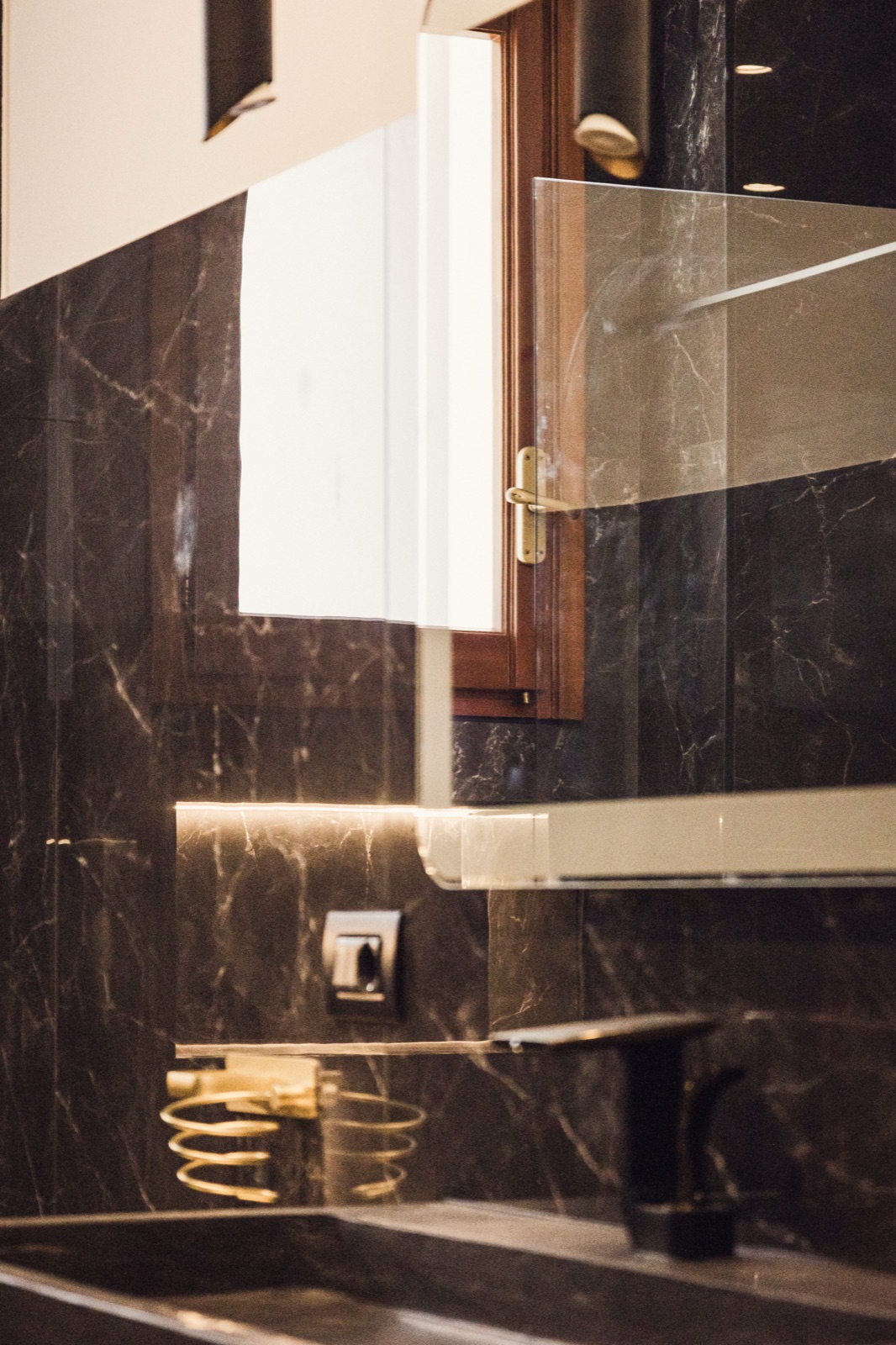 bagno in marmo nero con specchio e rubinetto oro