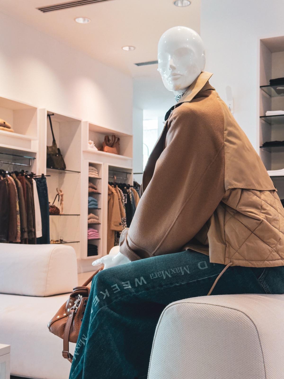 manichino seduto con cappotto cammello, interno negozio
