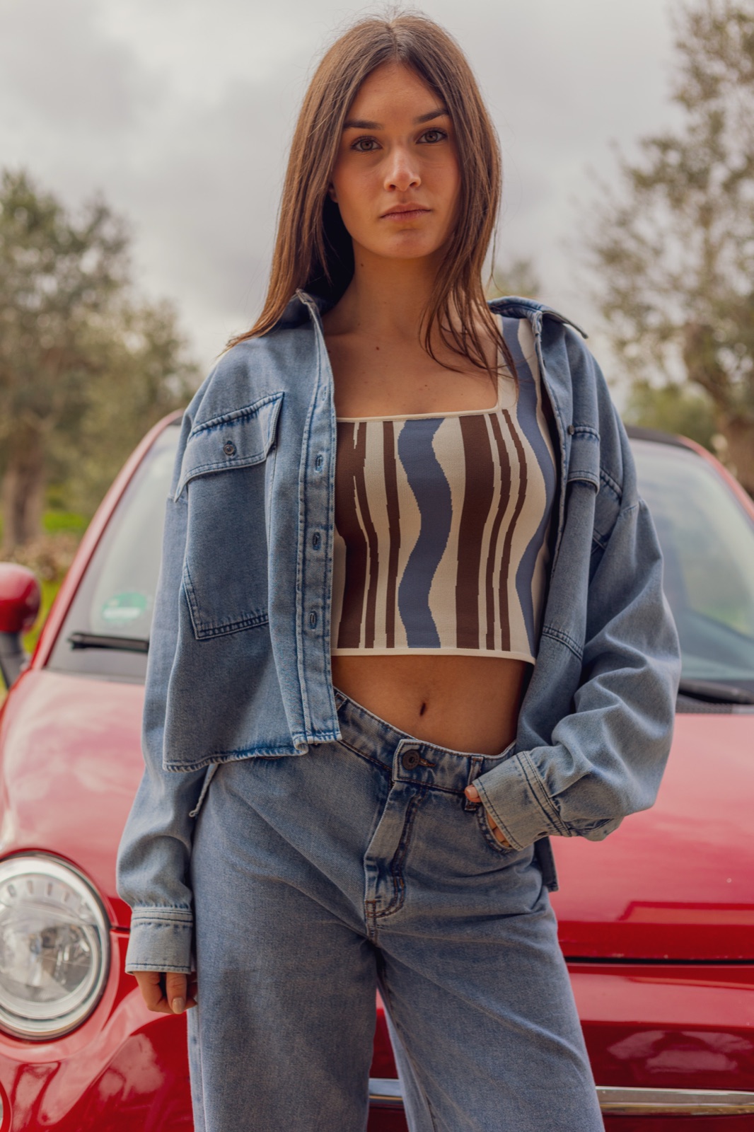 donna in denim con auto rossa d'epoca